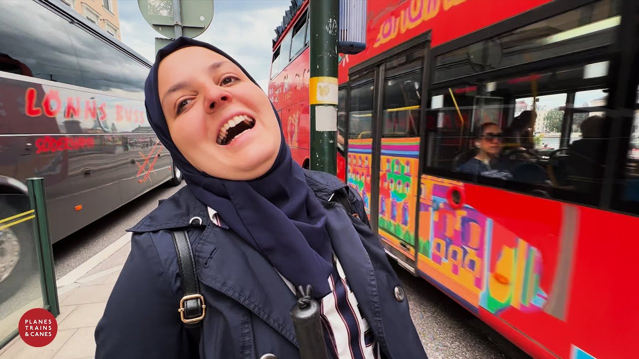 Mona laughing in a jolly mood infront of a red bus. 